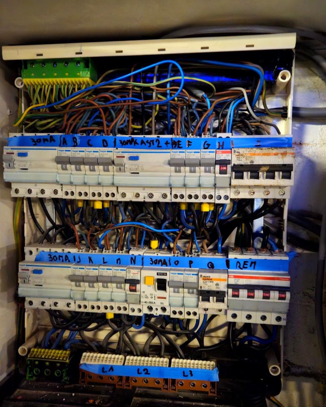 Oud verdeelbord met veel losse bedrading en met de hand beschreven tape boven de automaten