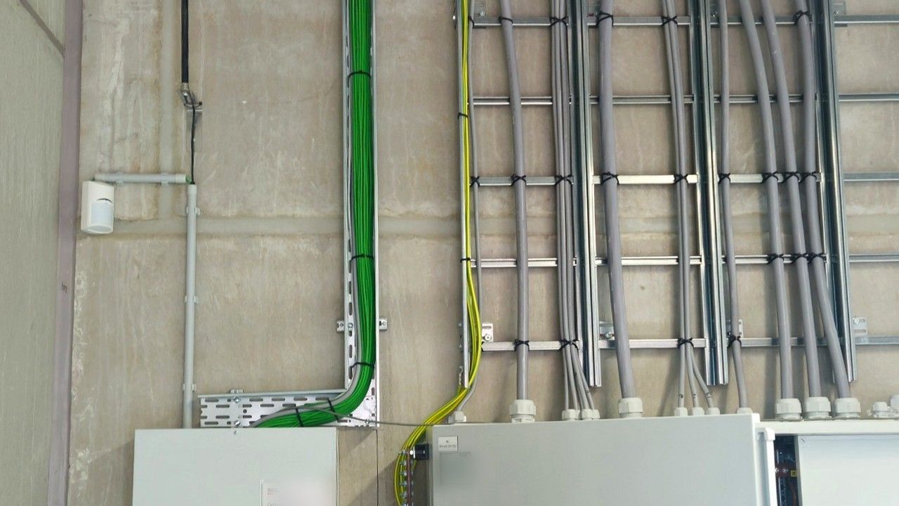 Betonwand met kabelladders en verdeelkasten in een technische ruimte, zonder meetkast