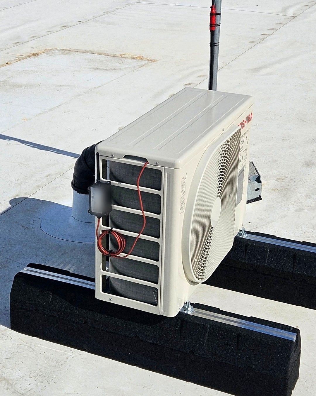 Draadloze temperatuursensor bevestigd op een buitenunit op een plat dak