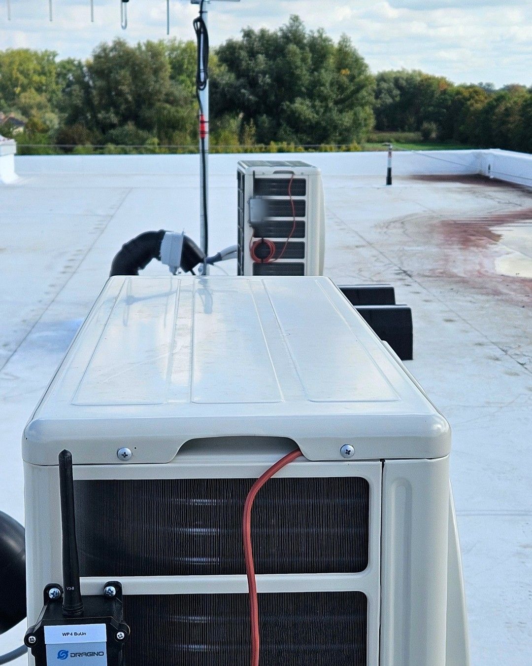 Twee buitenunits op een plat dak, elk met een draadloze sensor