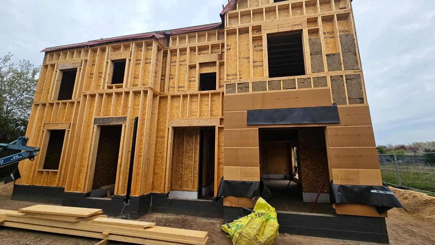 Twee aaneengesloten woningen in houtskeletbouw in ruwbouw, met OSB-platen en open raamgaten